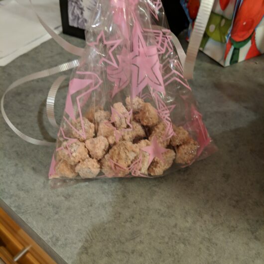 Candied almonds in a pink festive gift bag tied with a ribbon.