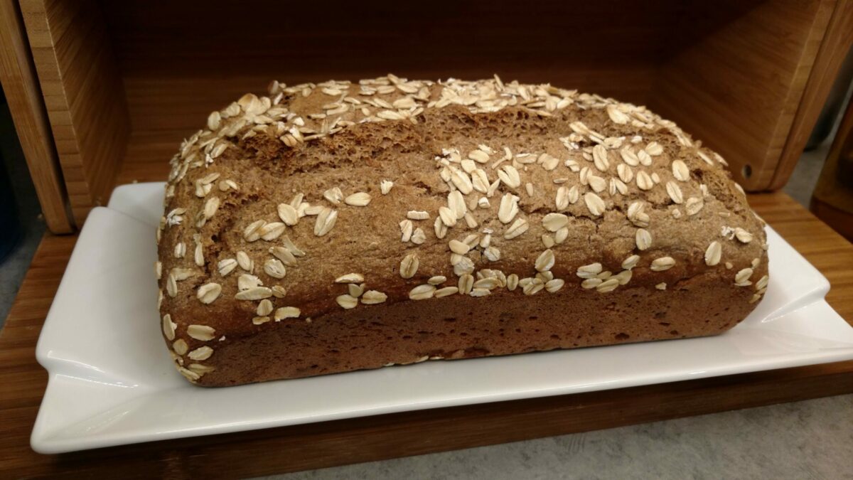 Homemade no-knead rye bread topped with oats, baked in a loaf tin.
